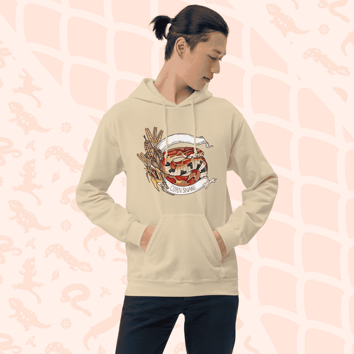 A man wearing beige pull over hoodie with a vibrant orange colored rat snake coiled in-between a white banner stating the species and glass corn on the left side.