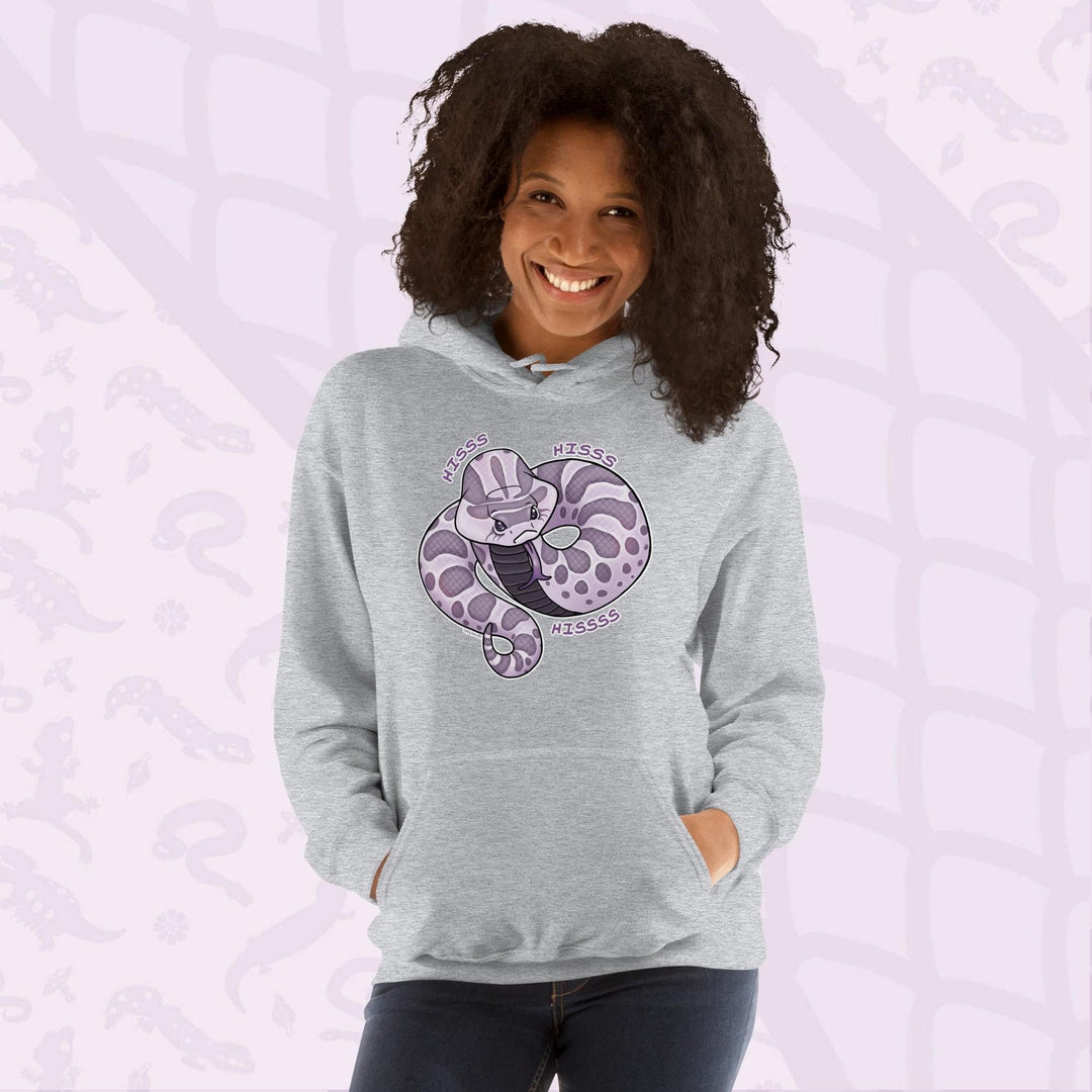 A woman wearing a light grey hoodie featuring a cartoon hognose snake design in shades of purple and gray. The snake is coiled and has the word "Hiss Hiss Hiss" printed around it. The hoodie has a front pocket and a hood.