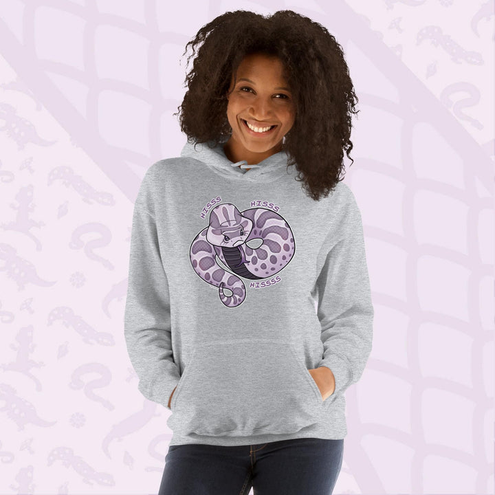 A woman wearing a light grey hoodie featuring a cartoon hognose snake design in shades of purple and gray. The snake is coiled and has the word "Hiss Hiss Hiss" printed around it. The hoodie has a front pocket and a hood.