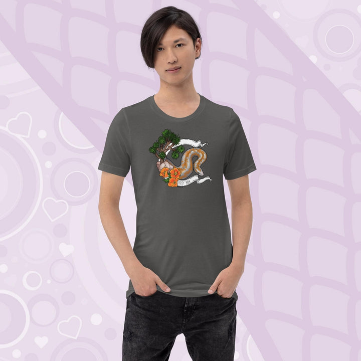 A man wearing a grey colored crew cut tee shirt on a light purple background. The art print on the front is a orange and grey speckled rosy boa snake framed by a white banner with California poppy flowers and a Joshua Tree on the left side of the design. The name Rosy Boa is written on the bottom of the banner.