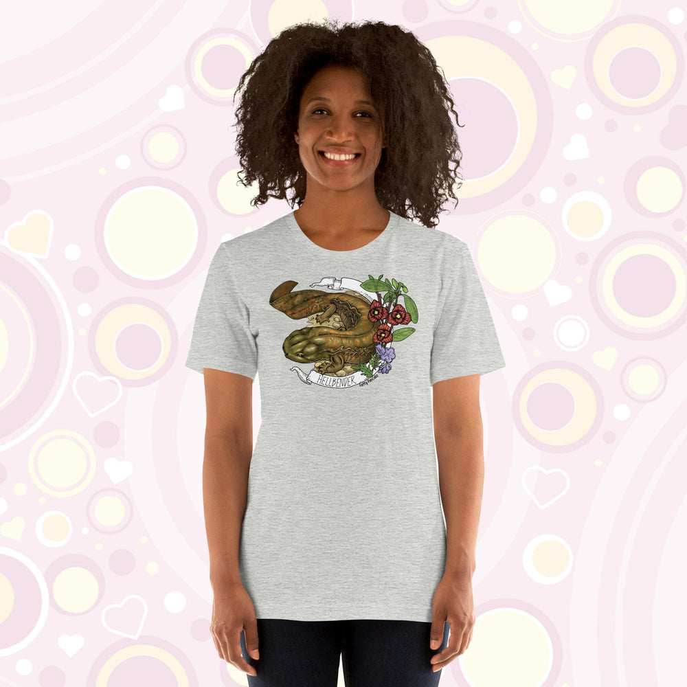 Lady wearing a grey crew neck tee with a hand drawn design of a hellbender amphibian framed by paw paw flowers and a banner that says, "Hellbender".