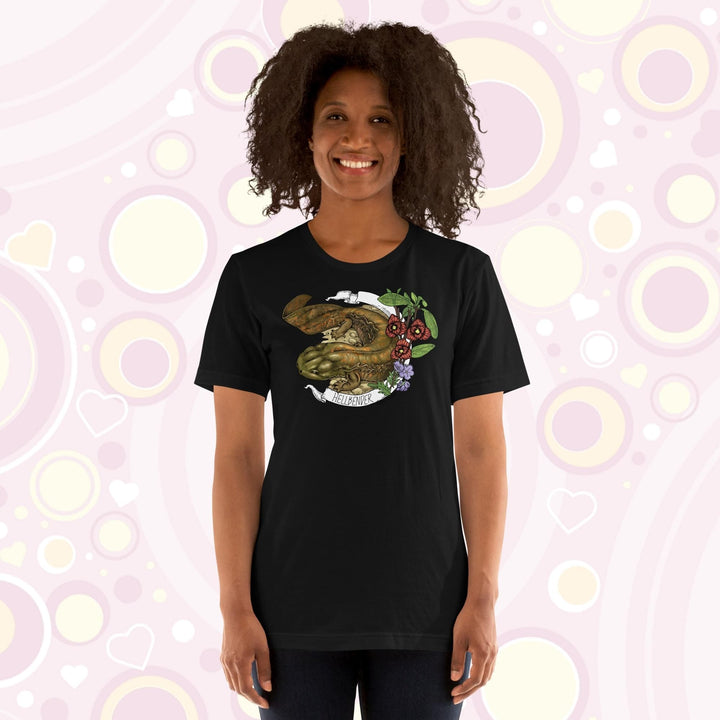 Lady wearing a black crew neck tee with a hand drawn design of a hellbender amphibian framed by paw paw flowers and a banner that says, "Hellbender".