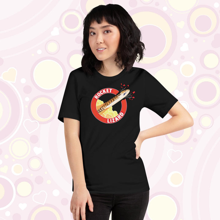 Lady wearing black crew neck tee with a circular design stating Rocket Lizard on the top and bottom and a cartoon blue tongue skink lizard blasting out from the side.