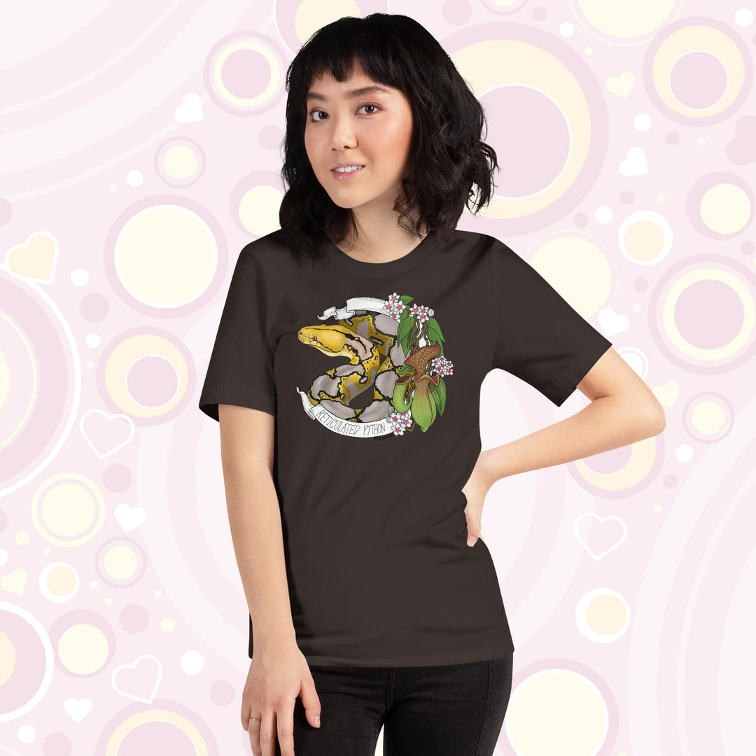 Image of a petite woman wearing a brown crew neck tee with a normal phase reticulated python framed by pitcher plants, white flowers, and a white banner with the text, "Reticulated Python" on it.