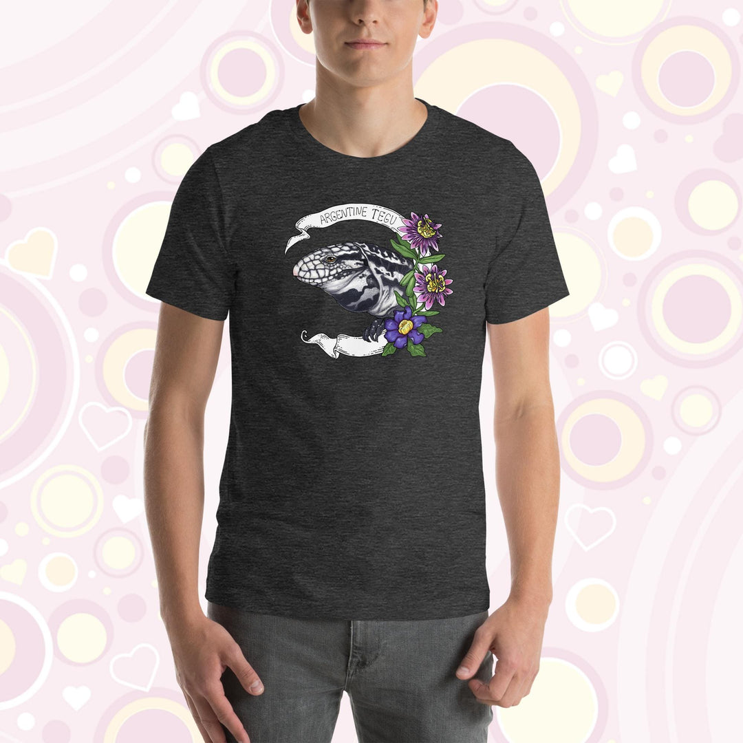 Man wearing grey crew neck tee with a hand drawn graphic of an Argentine Tegu lizard. Purple and pink flowers are on the right of the graphic and a white banner encircles the reptile.