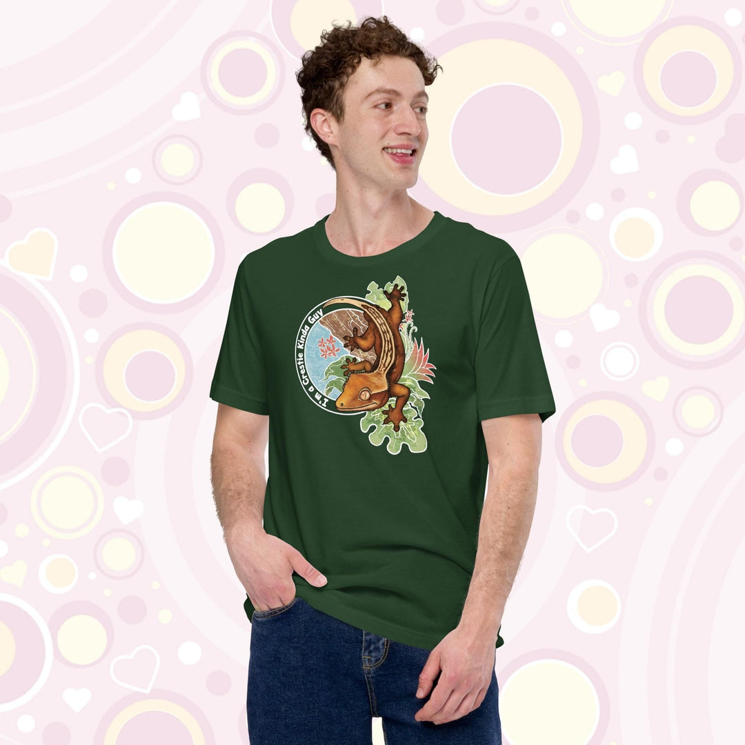 A man wearing a forest green crew neck tee with a graphic of a crested gecko climbing down from a tree with the words "I'm a crestie kind of guy" on the left hand side.