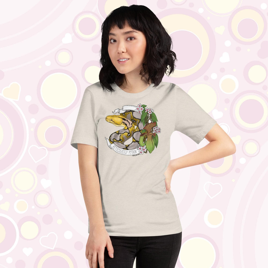 Image of a petite woman wearing a heather dust crew neck tee with a normal phase reticulated python framed by pitcher plants, white flowers, and a white banner with the text, "Reticulated Python" on it.