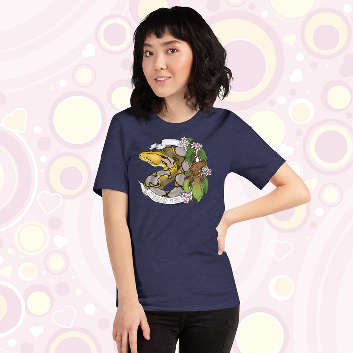 Image of a petite woman wearing a heather midnight blue crew neck tee with a normal phase reticulated python framed by pitcher plants, white flowers, and a white banner with the text, "Reticulated Python" on it.