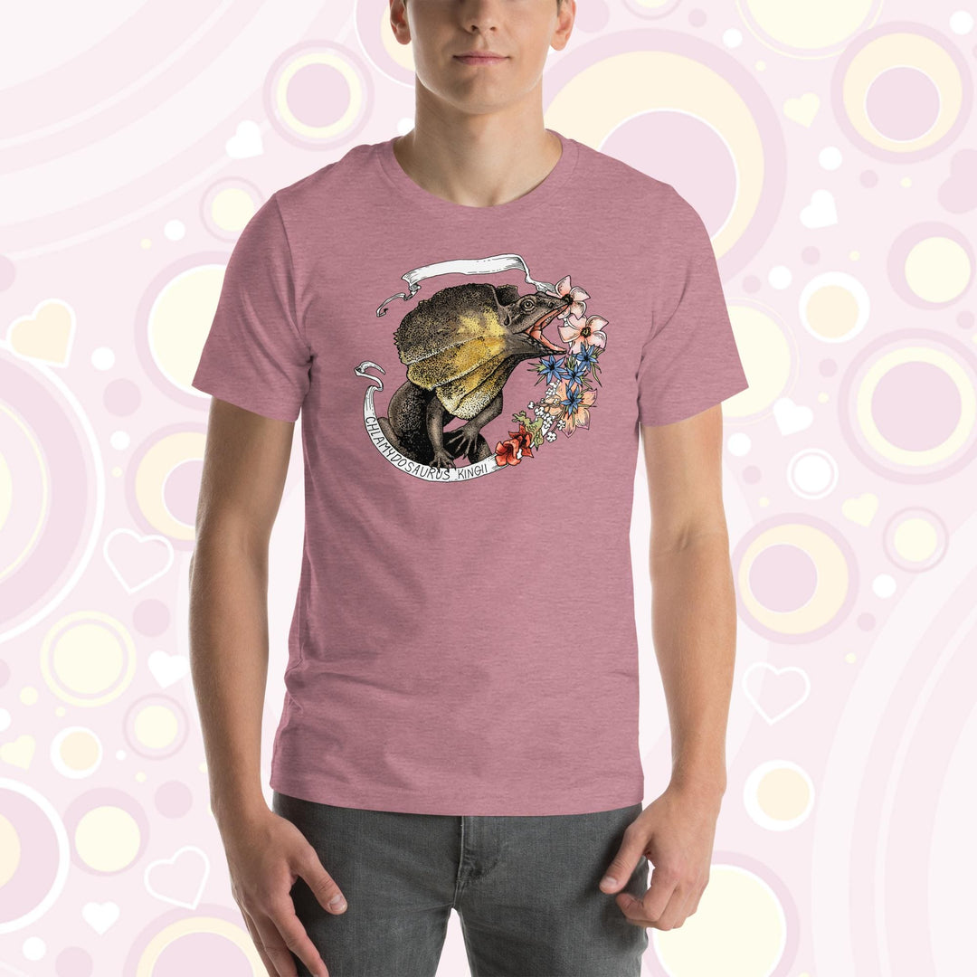 A man wearing a heather orchid crew neck tee with a frilled lizard from Australia on it. It has a banner with it's species name and pink, blue, and rose colored flowers on the right side.