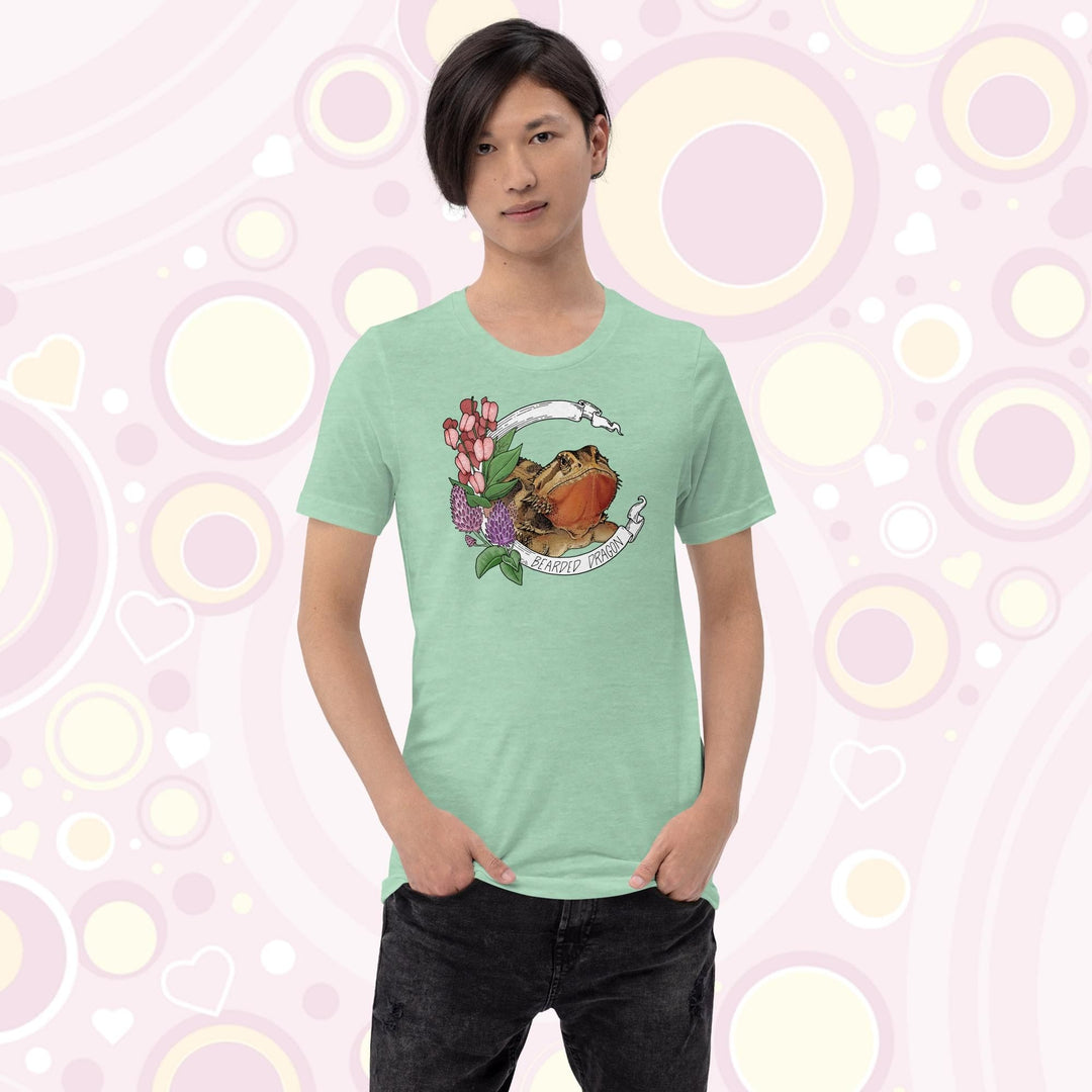 Image of a youth wearing a heather mint colored crew neck tee with a bearded dragon on it. The beardie is framed by a white banner with the text, "Bearded dragon" on the bottom and purple and red flowers adorning the left side of the design.