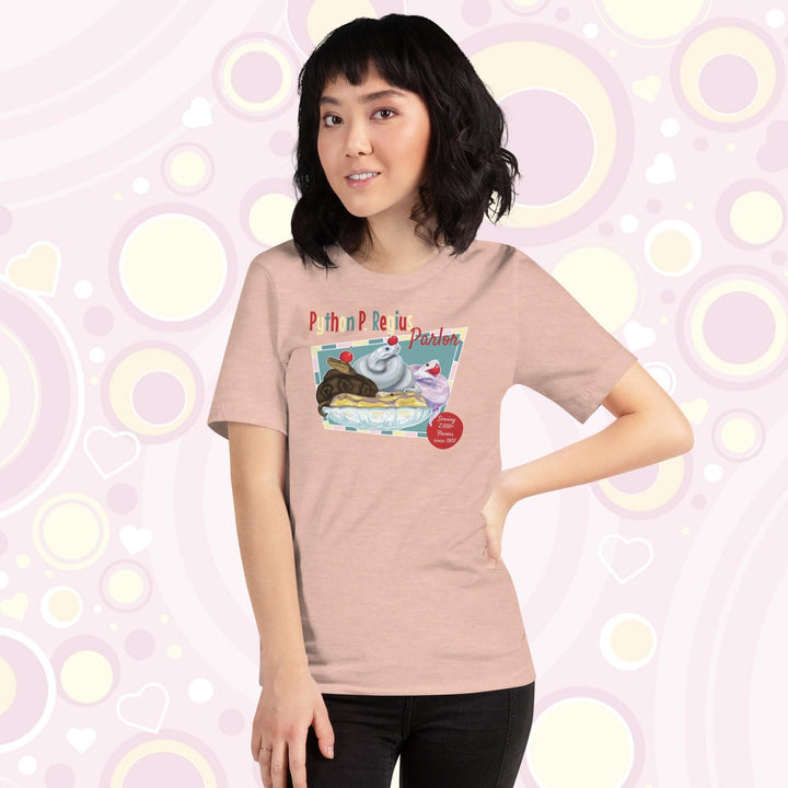 Lady wearing a peach crew neck tee showing a retro style design of 4 ball pythons in a banana split boat; one representing chocolate, strawberry, and vanilla ice cream and each topped with a sweet cherry! The text Python P Regius is on top in multi colors.