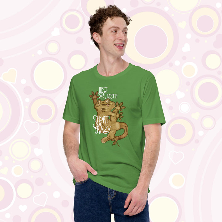 Man wearing green crew neck tee with the words "Just one Crestie Short of Crazy" with a crested gecko design clinging to the center. It's legs are flung out and it has a silly expression.