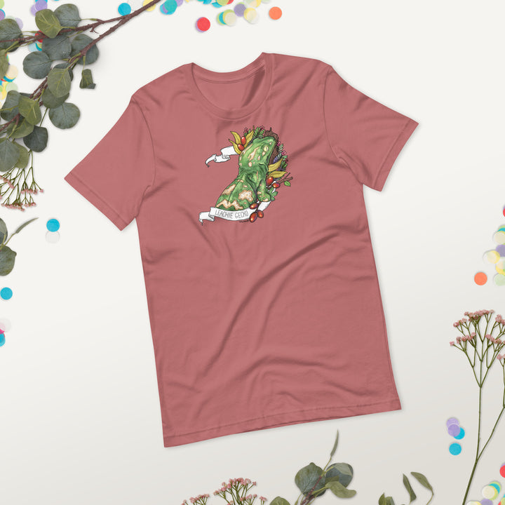 Mauve colored t-shirt with a graphic of a leachie gecko on a light background with decorative plant elements.