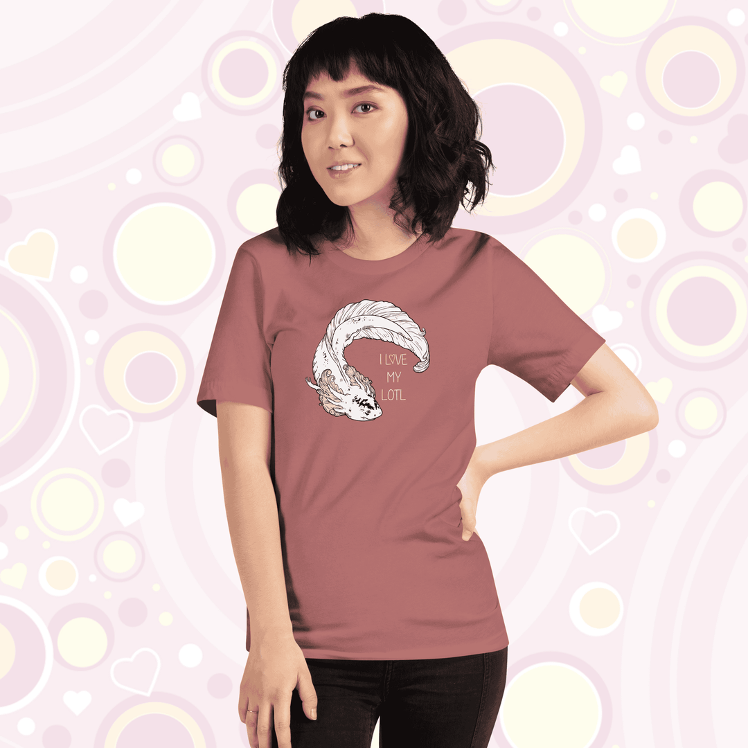 Lady wearing mauve crew neck tee with a white axolotl with black speckles on it's nose and pink gills that have very delicate line art on it. There is text that reads I love my lotl.