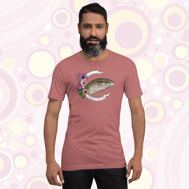 Man wearing mauve crew neck tee with a head shot of a savannah monitor lizard with purple flowers on the side and a white banner encircling the design which says the species name.