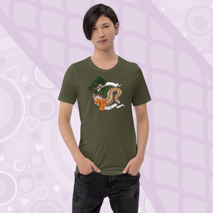 A man wearing a military green colored crew cut tee shirt on a light purple background. The art print on the front is a orange and grey speckled rosy boa snake framed by a white banner with California poppy flowers and a Joshua Tree on the left side of the design. The name Rosy Boa is written on the bottom of the banner.