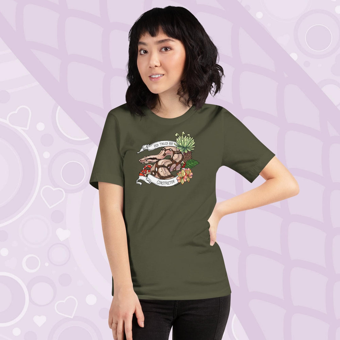 A woman wearing a green crew necked tee with a graphic of a red-tailed boa constrictor with floral elements and a white banner encircling it. 