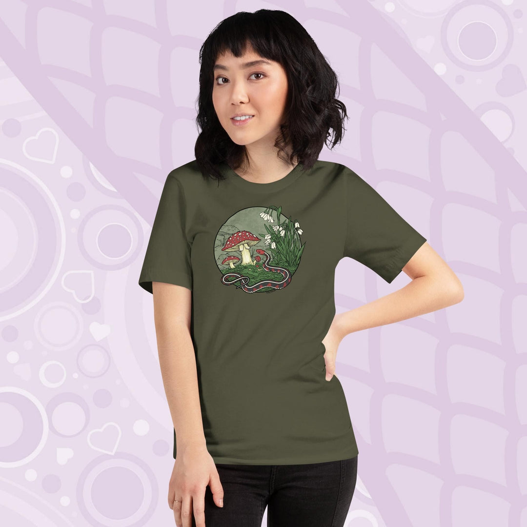 A woman wearing a military green tee shirt with a graphic of a red sided garter snake, surrounded by mushrooms and plants with white blossoms. It has simple colors of red, white, and green.  It has lineart outlining the entire illustration.