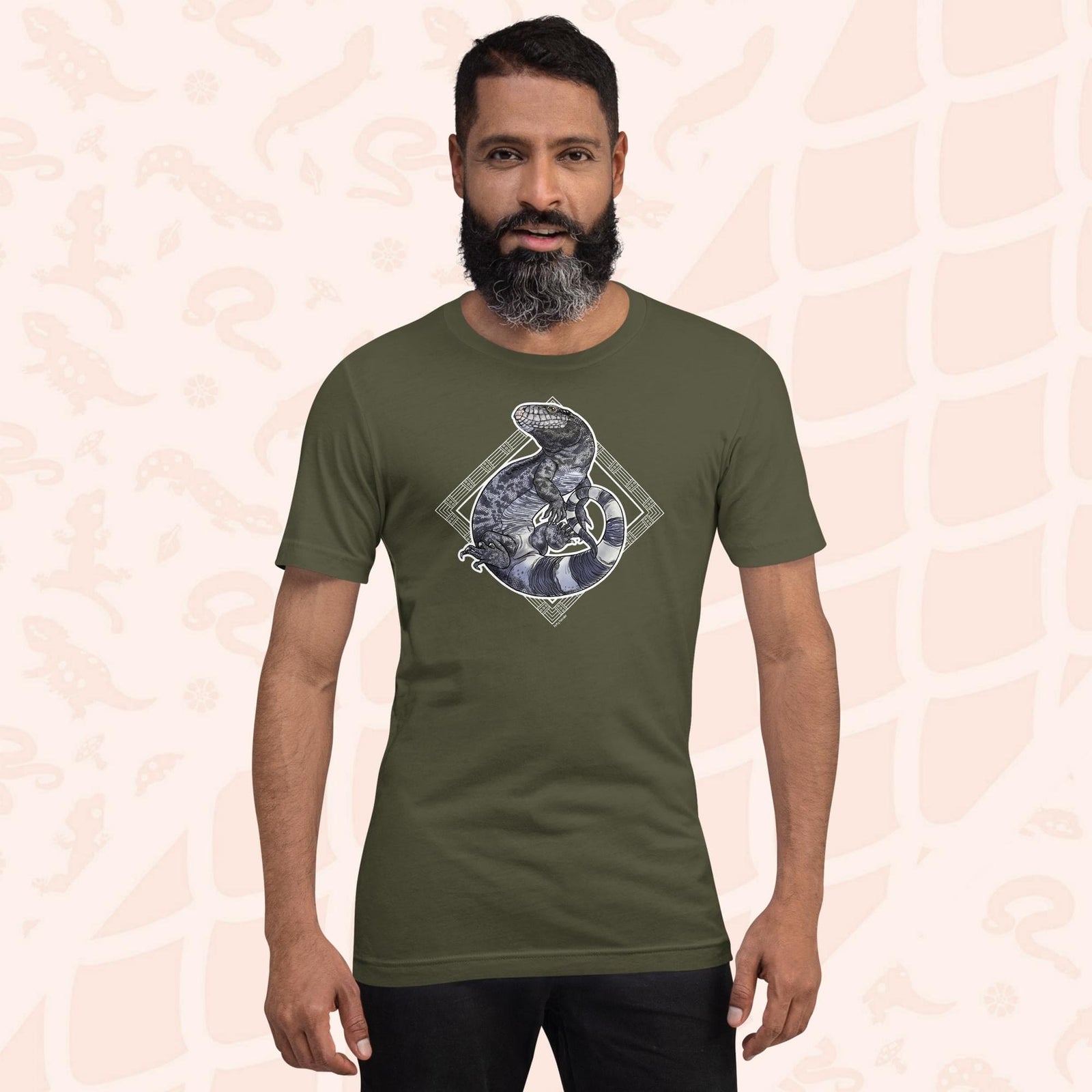 Man wearing a military green colored unisex crew neck tee with a graphic of a black and white tegu curled up in a graphic element.
