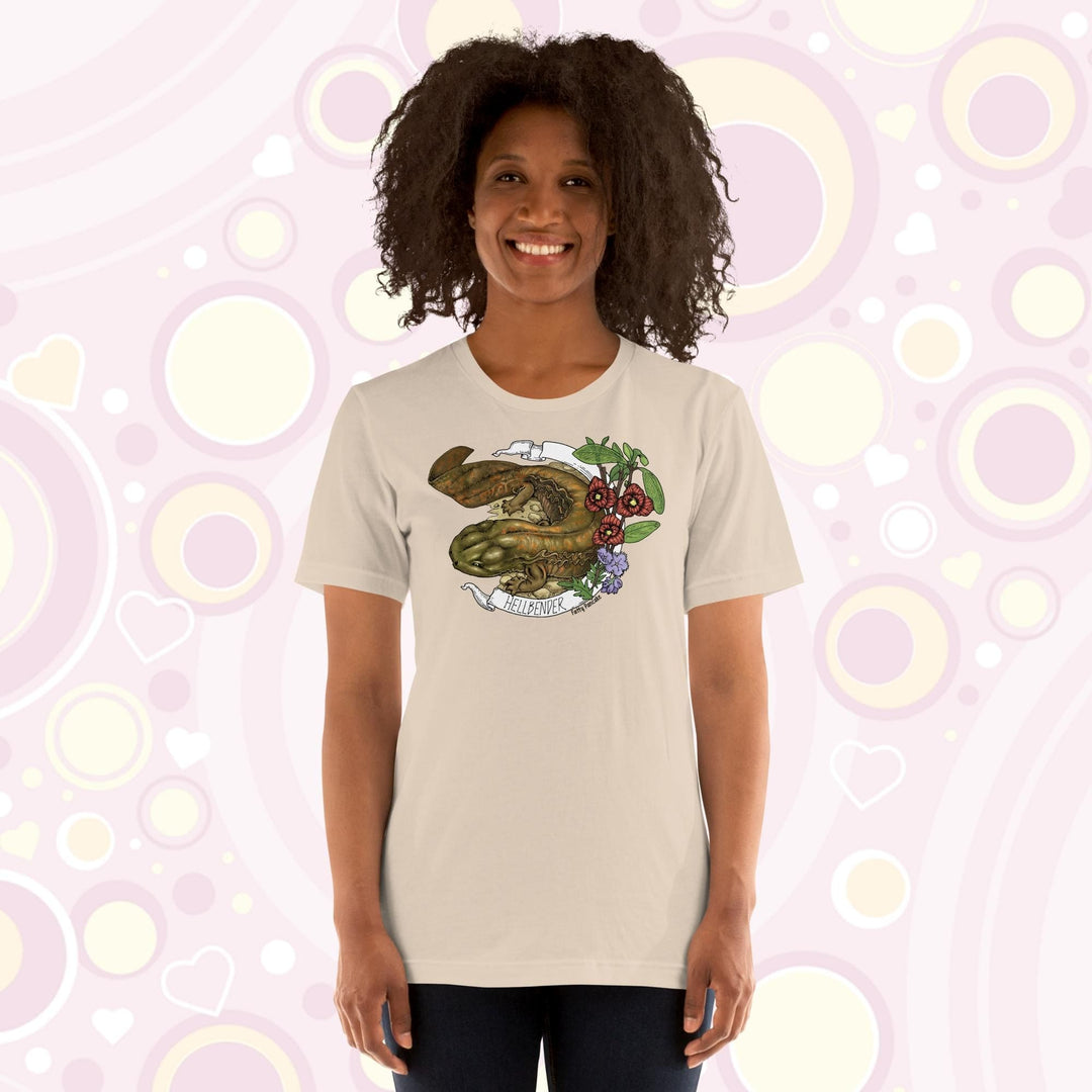 Lady wearing a cream crew neck tee with a hand drawn design of a hellbender amphibian framed by paw paw flowers and a banner that says, "Hellbender".