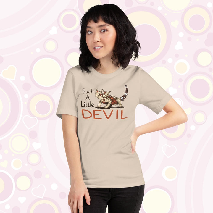 Woman wearing soft cream colored crew neck tee with a thorny devil lizard on it with text that reads: "Such a little Devil".