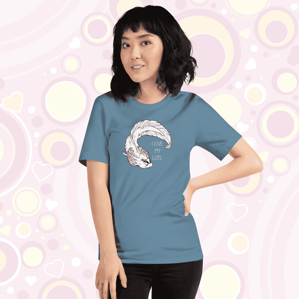 Lady wearing steel blue crew neck tee with a white axolotl with black speckles on it's nose and pink gills that have very delicate line art on it. There is text that reads I love my lotl.