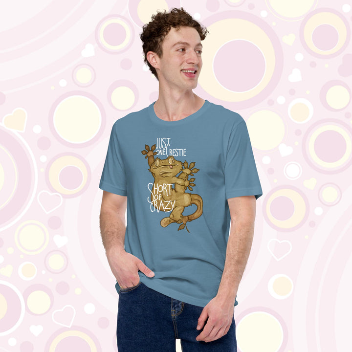 Man wearing steel blue crew neck tee with the words "Just one Crestie Short of Crazy" with a crested gecko design clinging to the center. It's legs are flung out and it has a silly expression.