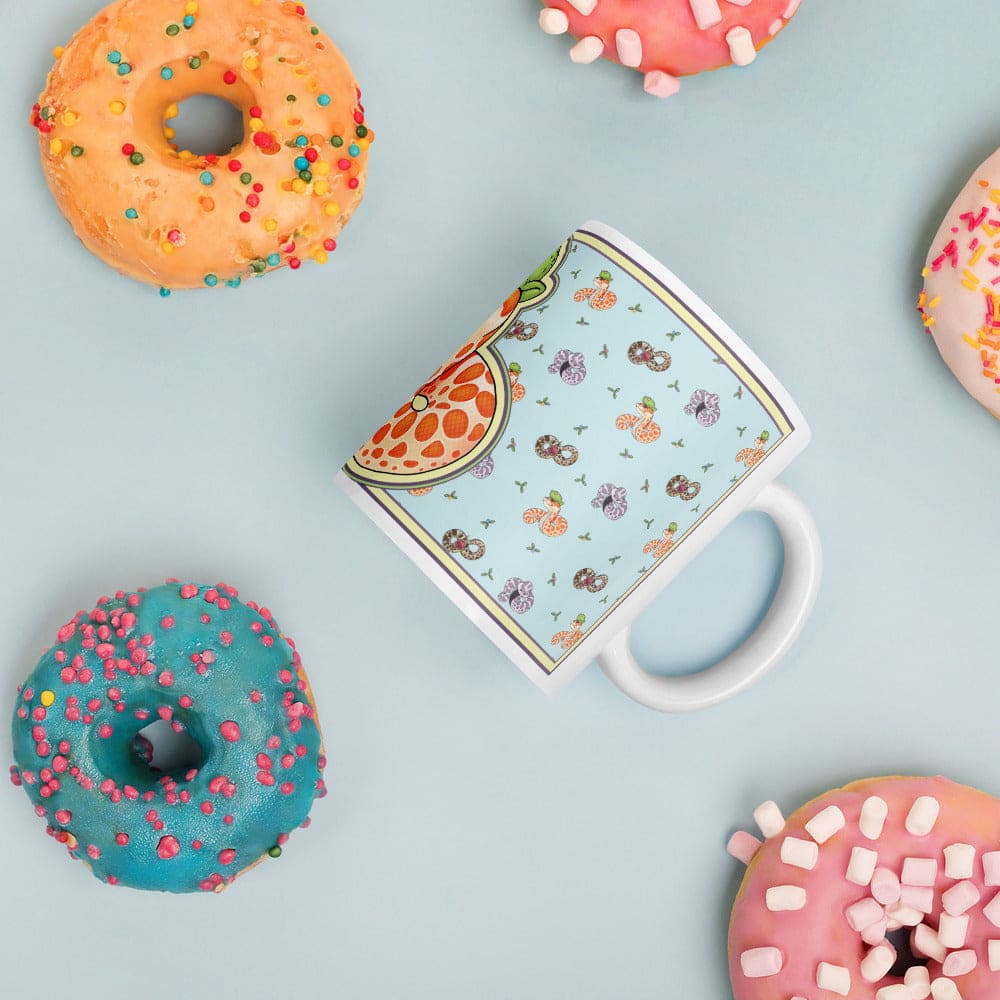 Image of a 11oz mug with a ceramic mug on it's side surrounded by colorful donuts on a soft blue background. 