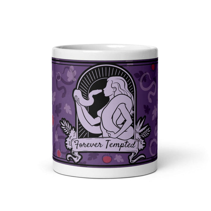 A 11oz white ceramic mug featuring a purple graphic illustration of a figure holding a snake within an arched frame. The text Forever Tempted is printed on a banner below the figure, surrounded by a pattern of leaves and red apples.