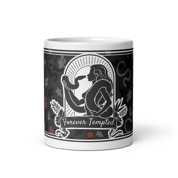A 11oz white ceramic mug featuring a black and white graphic illustration of a figure holding a snake within an arched frame. The text Forever Tempted is printed on a banner below the figure, surrounded by a pattern of leaves and red apples.