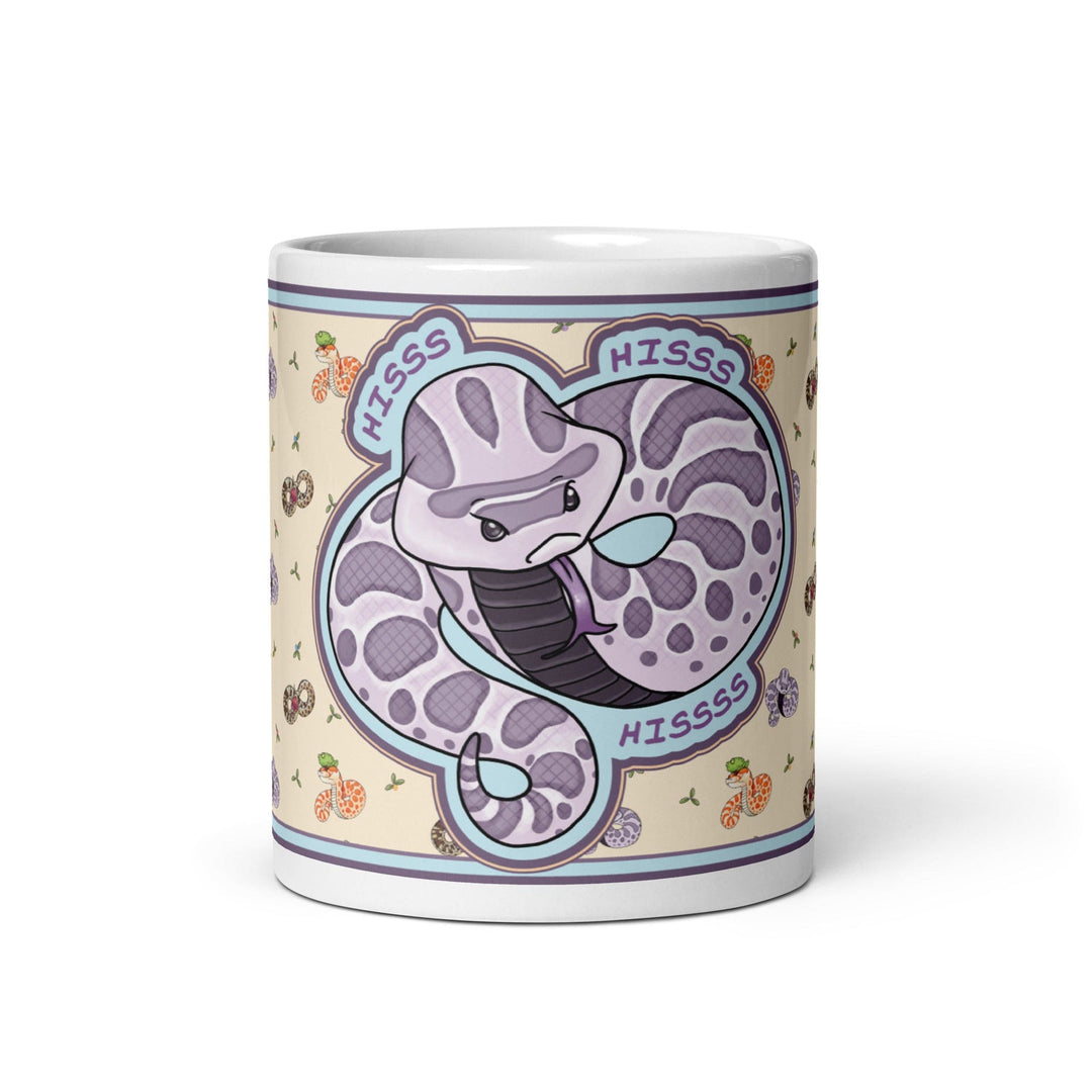 Front side of the 11oz Hognose Hiss Hiss Hiss mug. The mug has a full color wrap with some white ceramic on the handle and top and bottom. The design is cute, cartoony, with a lavender angry hoggie hissing dramatically against a pale yellow background with tiny hognoses and flowers.