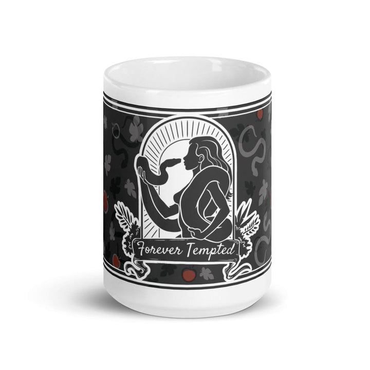 A 15oz white ceramic mug featuring a black and white graphic illustration of a figure holding a snake within an arched frame. The text Forever Tempted is printed on a banner below the figure, surrounded by a pattern of leaves and red apples.
