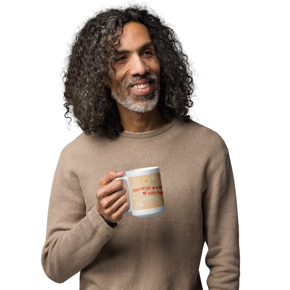A man holding a white ceramic mug featuring a light tan background with circular patterns and small heart icons. The text printed on the mug reads, "Mornings are better with Pandas" in red lettering, accompanied by a small red heart symbol between the words.