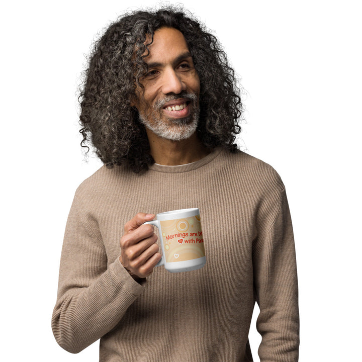 A man holding a white ceramic mug featuring a light tan background with circular patterns and small heart icons. The text printed on the mug reads, "Mornings are better with Pandas" in red lettering, accompanied by a small red heart symbol between the words.