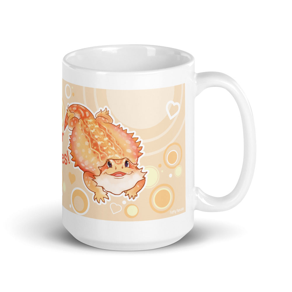 A white ceramic mug featuring a cute cartoon illustration of a bearded dragon on a warm beige background with orange, yellow, and white circular and heart accents.