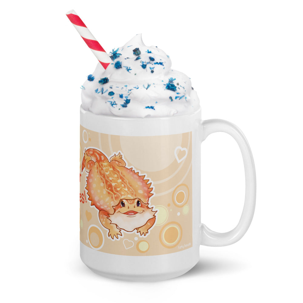 A white ceramic mug with a cartoon bearded dragon illustration on a beige background, filled with whipped cream, blue sprinkles, and a red-and-white striped straw, shown on a white background.