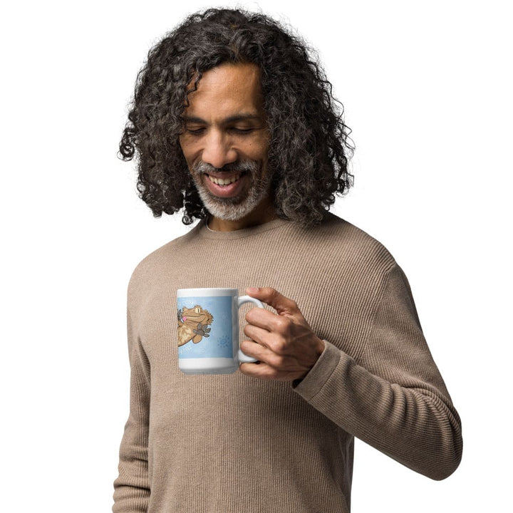 A man standing against a white background holding a blue mug with a cartoon crested gecko.