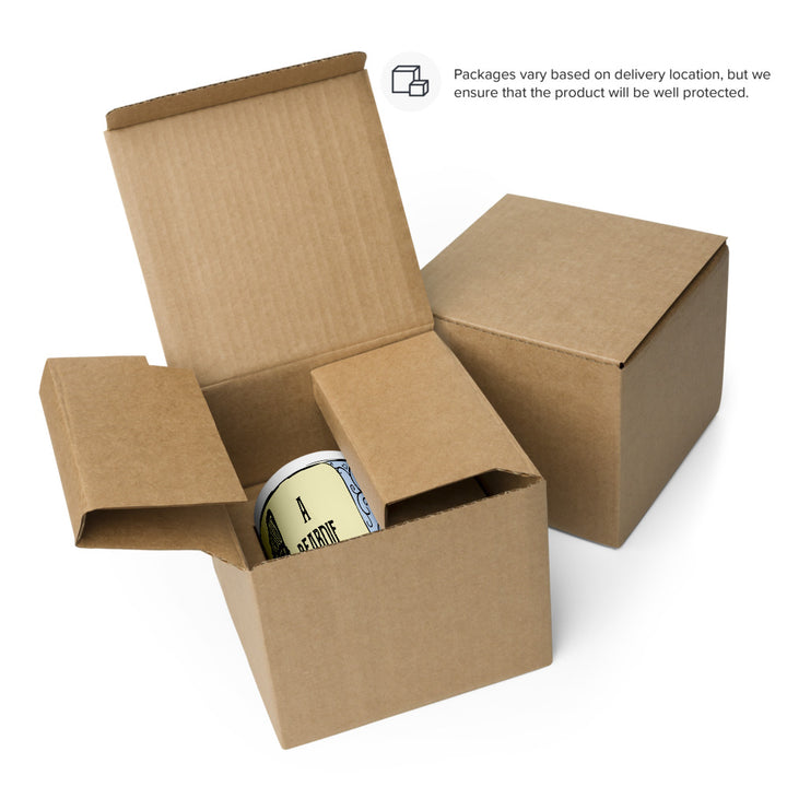 Two brown cardboard shipping boxes, one closed and one open, revealing a white ceramic mug inside. The mug features a pale yellow background with black text that reads A BEARDIE, partially visible within the protective packaging.