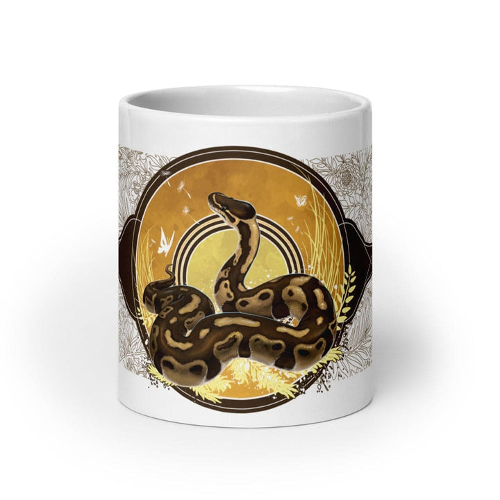 A white 20oz mug of a normal phase ball python with gold and warm colors in a autumn like setting sitting on a white background. 