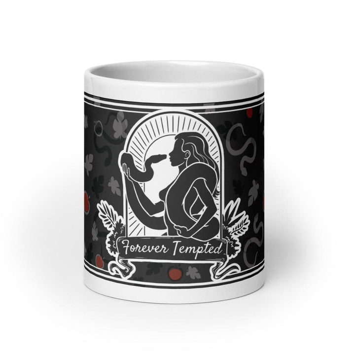 A 20oz white ceramic mug featuring a black and white graphic illustration of a figure holding a snake within an arched frame. The text Forever Tempted is printed on a banner below the figure, surrounded by a pattern of leaves and red apples.