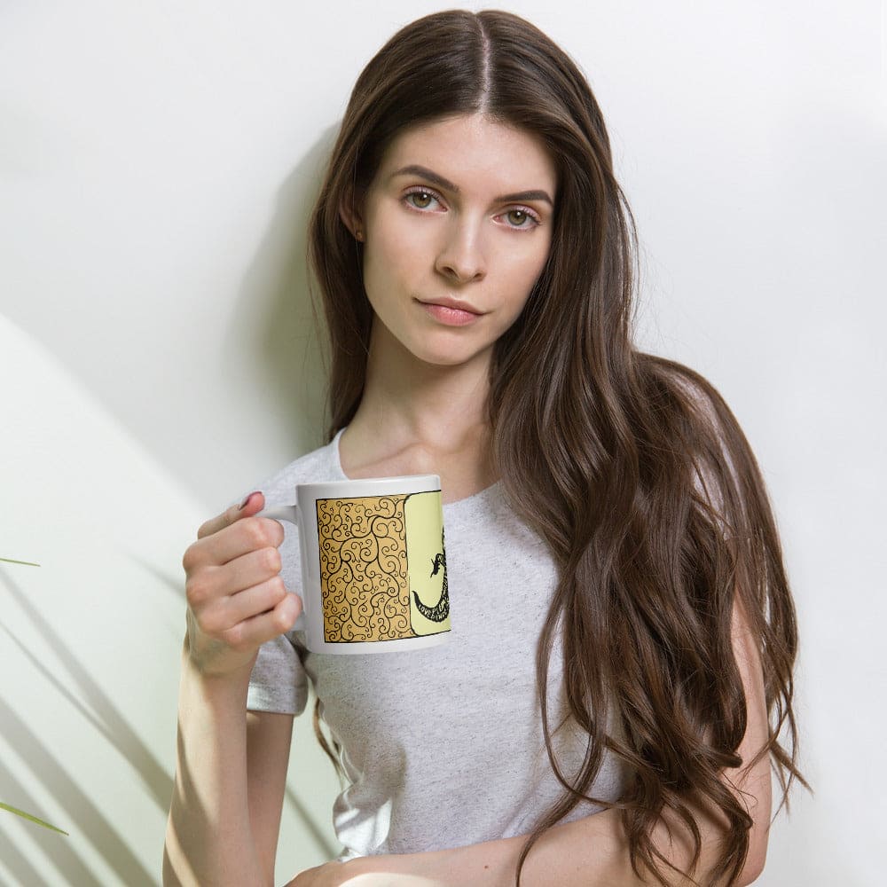 A woman holding a yellow mug with a leopard gecko design on the front sitting in front of a white background.