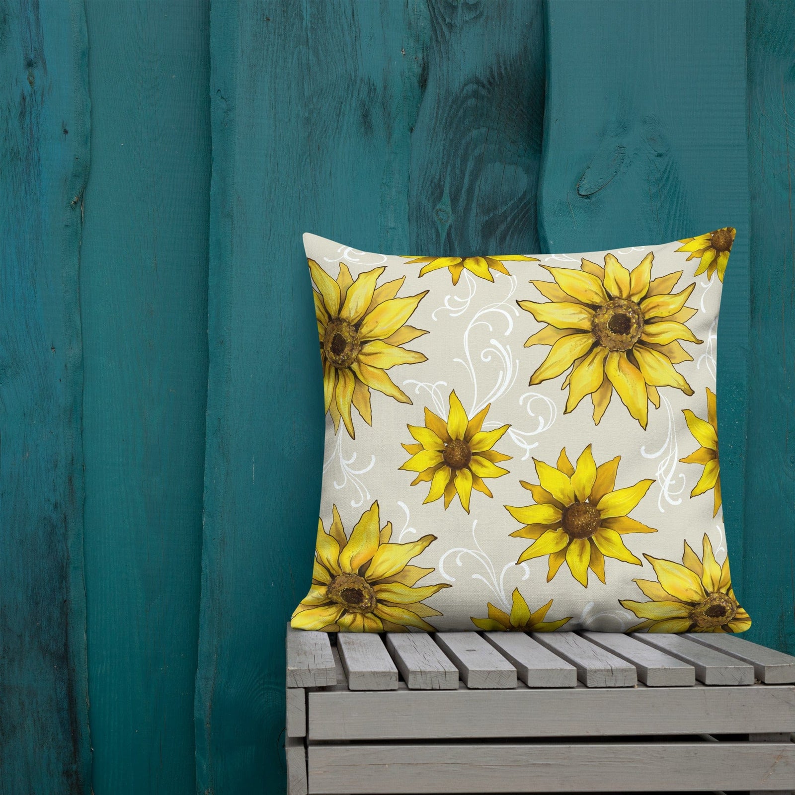 Rear view of the square pillow showing sunflowers and white decorative elements, placed on a wooden surface with a blue wall in the background. Pillow measures 22 inch x 22 inch.